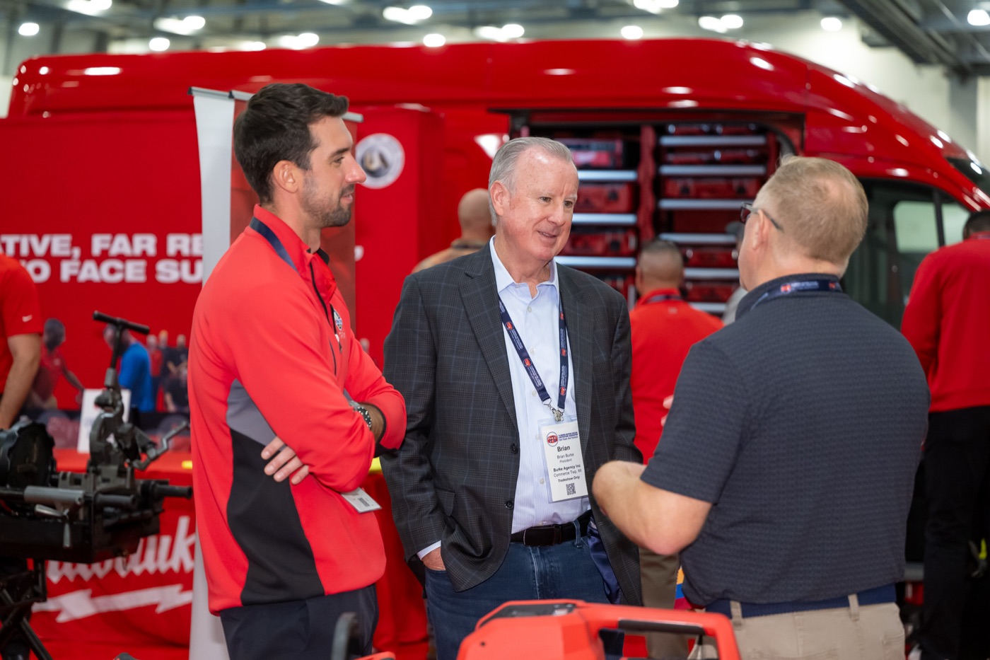 The big red Milwaukee Tool van on the show floor, racks open, reps talking with contractors